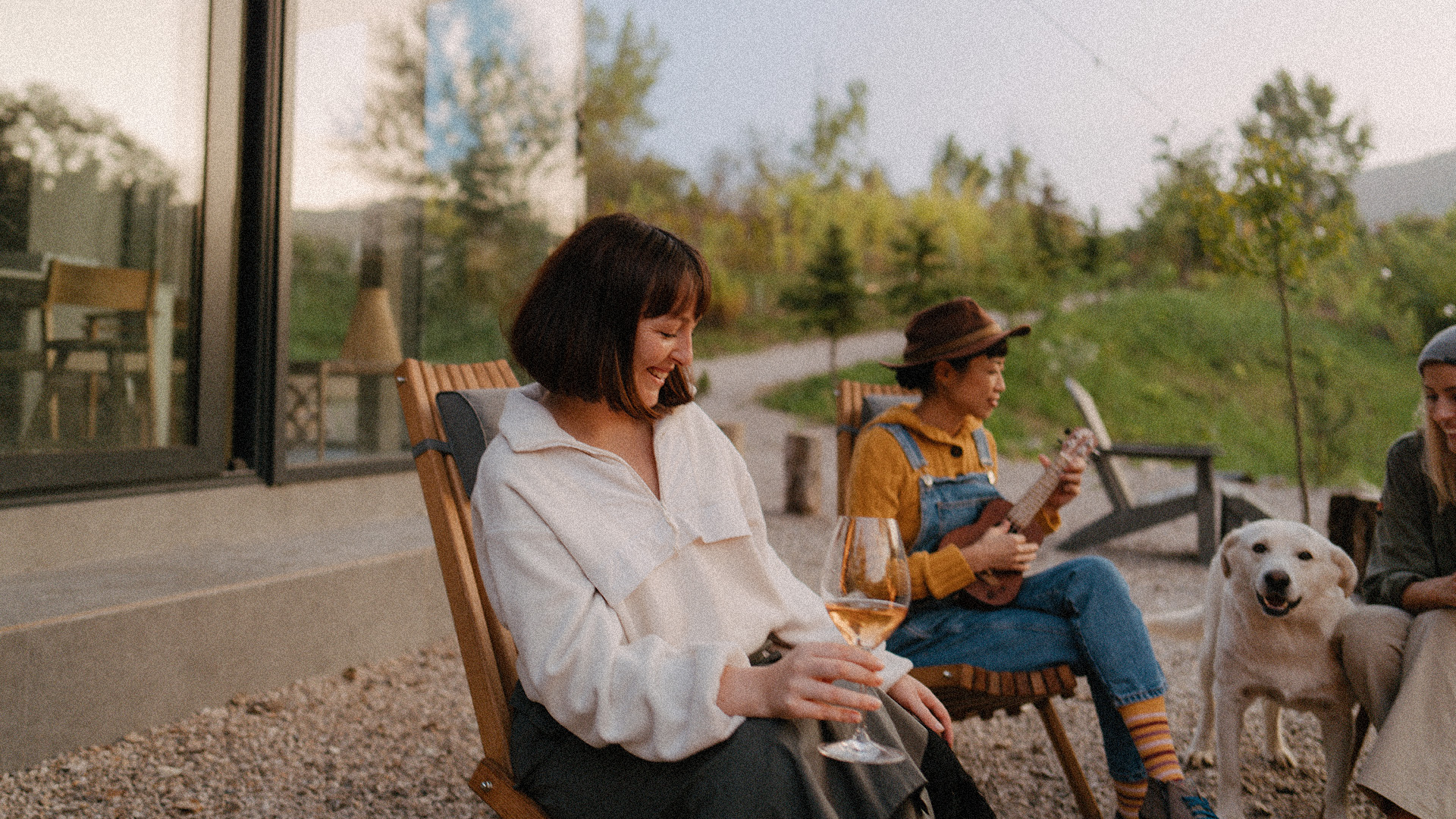 friends sit outside of their modern home in the mountains enjoying music and wine - new homes at Big Sky Quarry